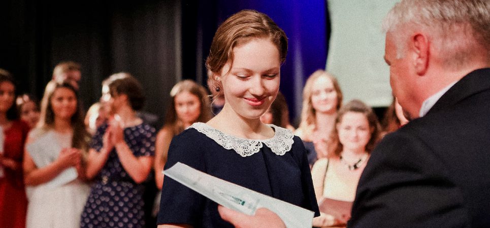 A photo of Ieva receiving her degree. she is smiling.